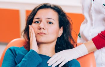 Upset woman having a toothache and holding hand on her cheek