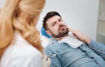 I cannot take it any longer. Disturbed handsome upset man telling a doctor about his concerns while paying her a regular visit and sitting in dentists chair