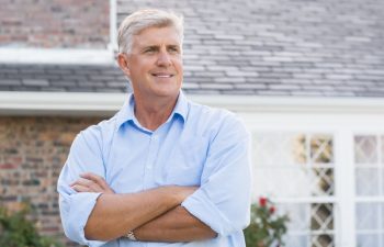 Successful happy retired man standing with crossed arm. Senior man thinking and looking away. Portrait of old man feeling good to retire.