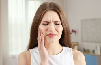 Young woman suffering from toothache at home