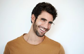 Guy in glasses smiling against white background