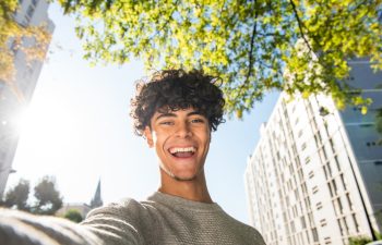 Portrait happy young man taking selfie outside in city