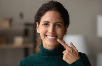 Shiny smile. Portrait of young happy hispanic woman satisfied patient of dental clinic. Millennial lady enjoy perfect result of orthodontic care procedures look at camera point on white straight teeth