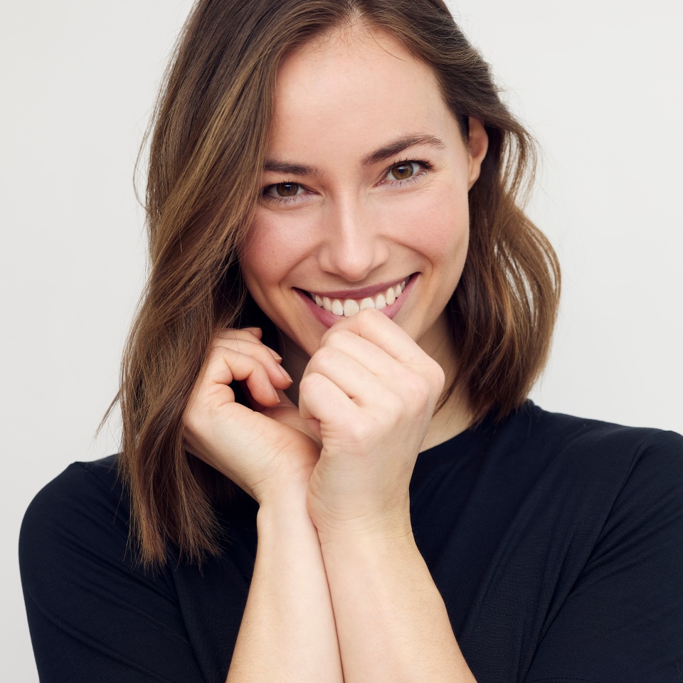 Portrait of beautiful young female or woman looking happy and confident in camera. Big smile on her face, looking beautiful standing isolated on white background. Concept: having a secret.