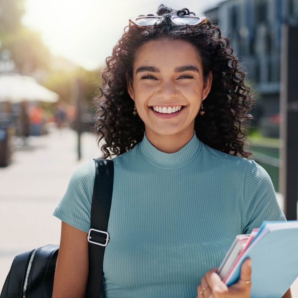 Woman, portrait and outdoor happiness at university, books for education or learning on campus. Female student, smile and notes for knowledge at college, academy scholarship for school in Canada